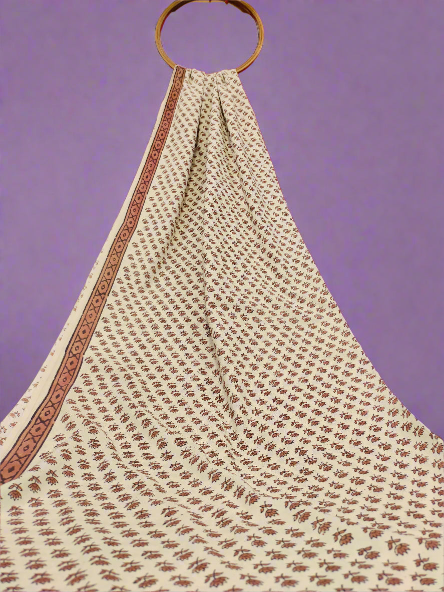 White fabric with brown patterns draped over a wooden ring against a red curtain.