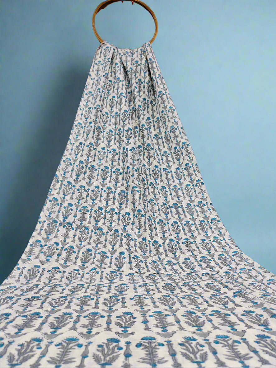 Fabric with blue floral pattern draped over a wooden hanger against a red curtain.