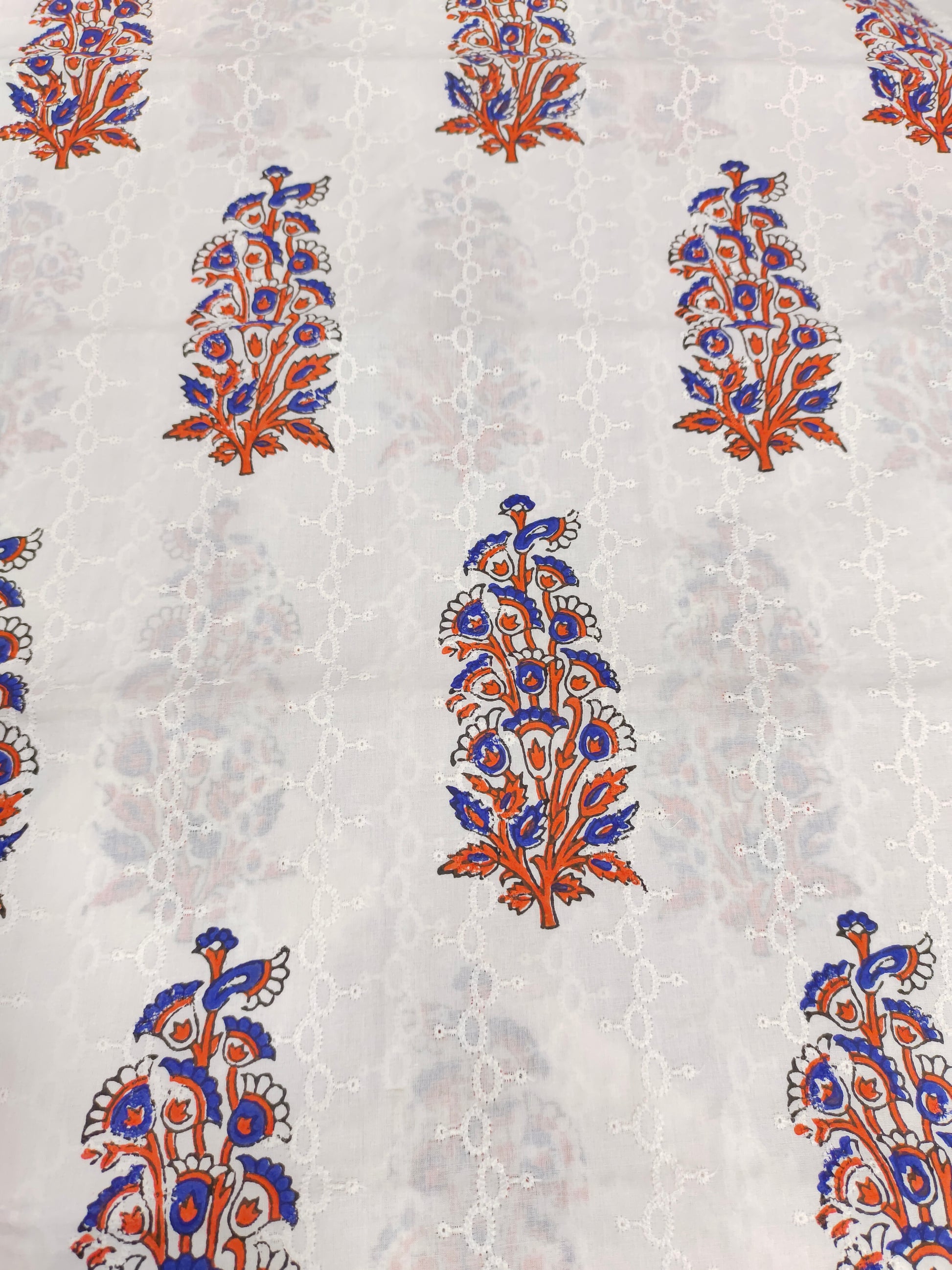 White embroidered fabric with blue and orange handblock print