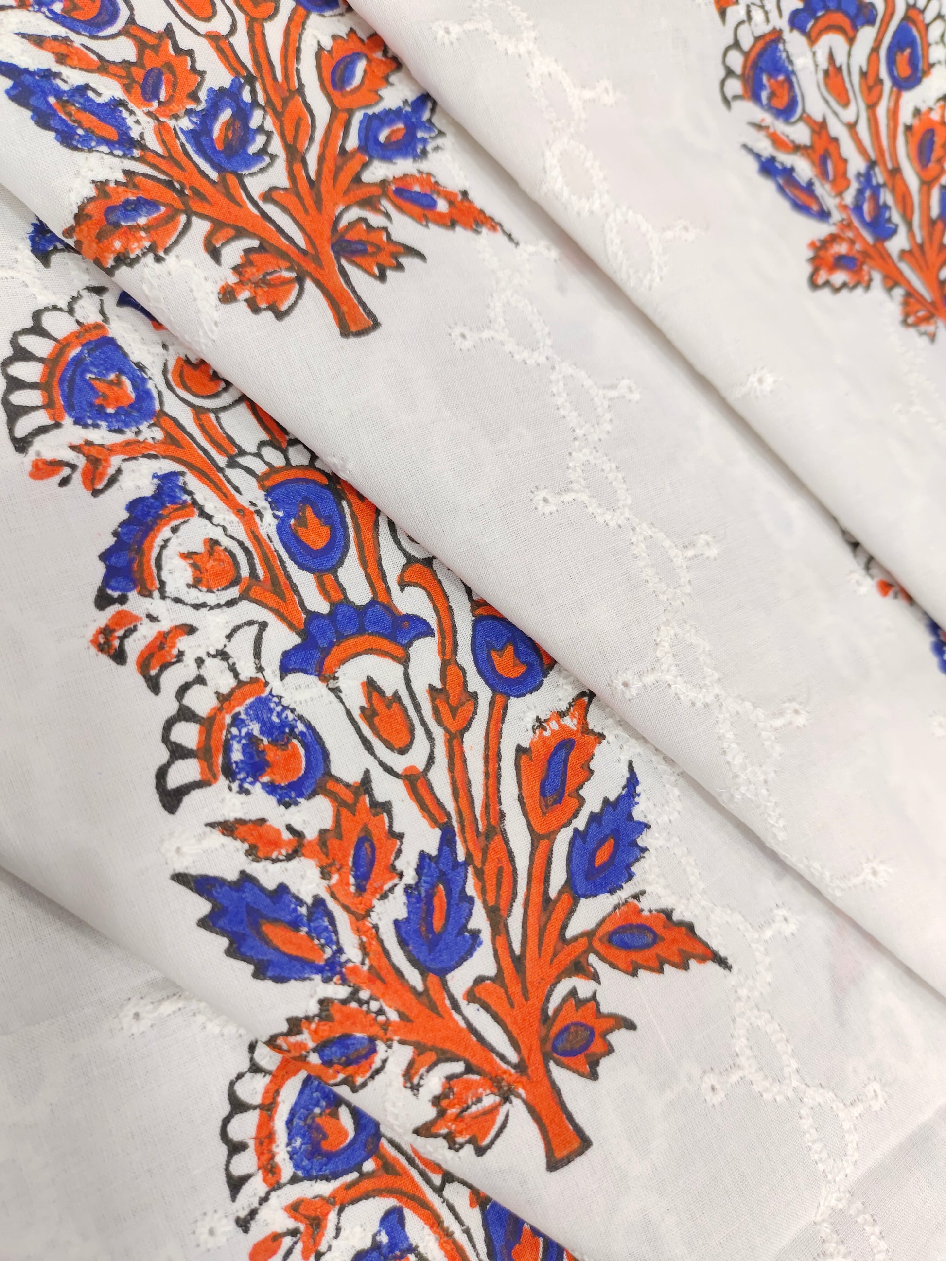 White embroidered fabric with blue and orange handblock print