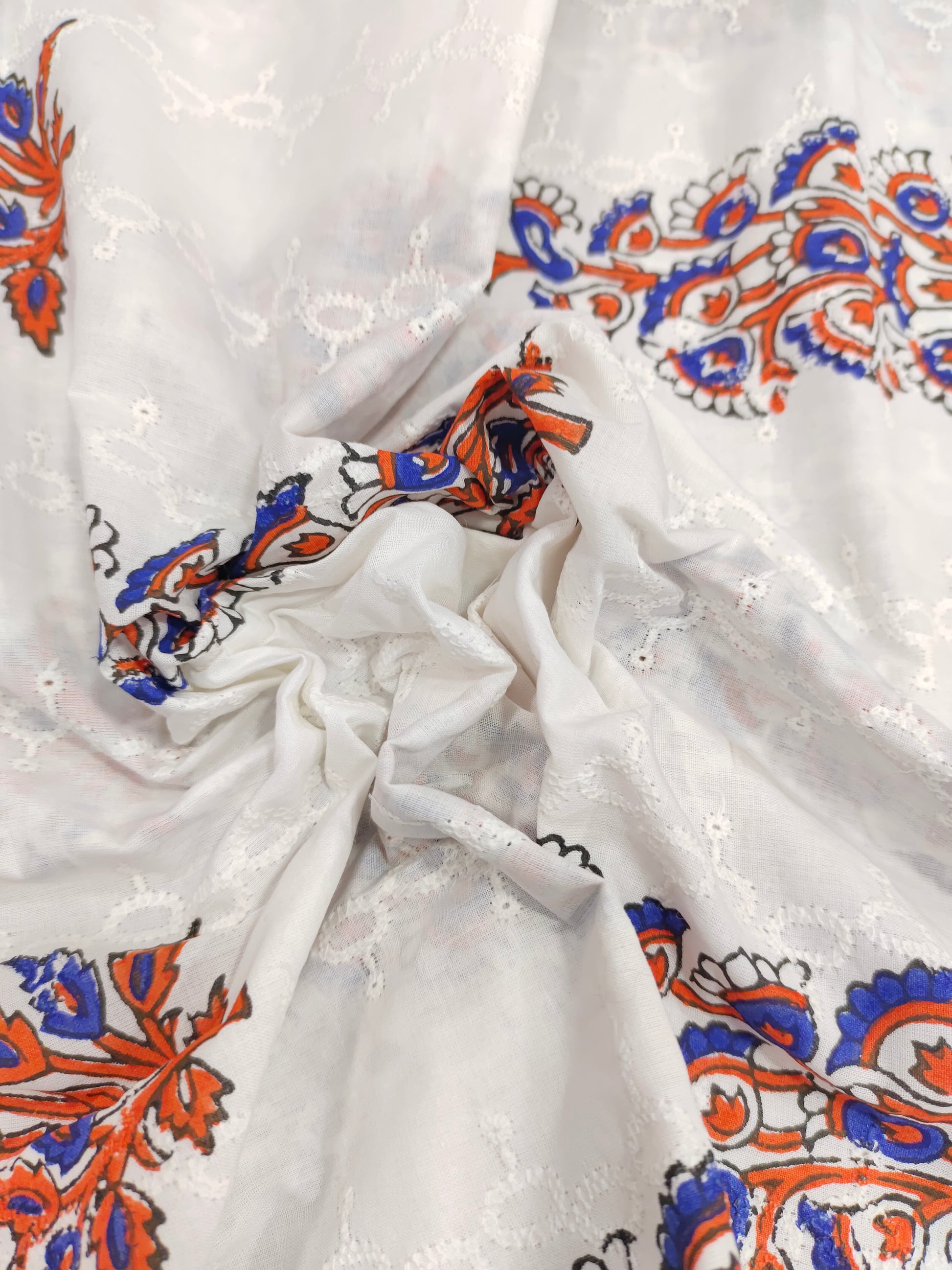 White embroidered fabric with blue and orange handblock print
