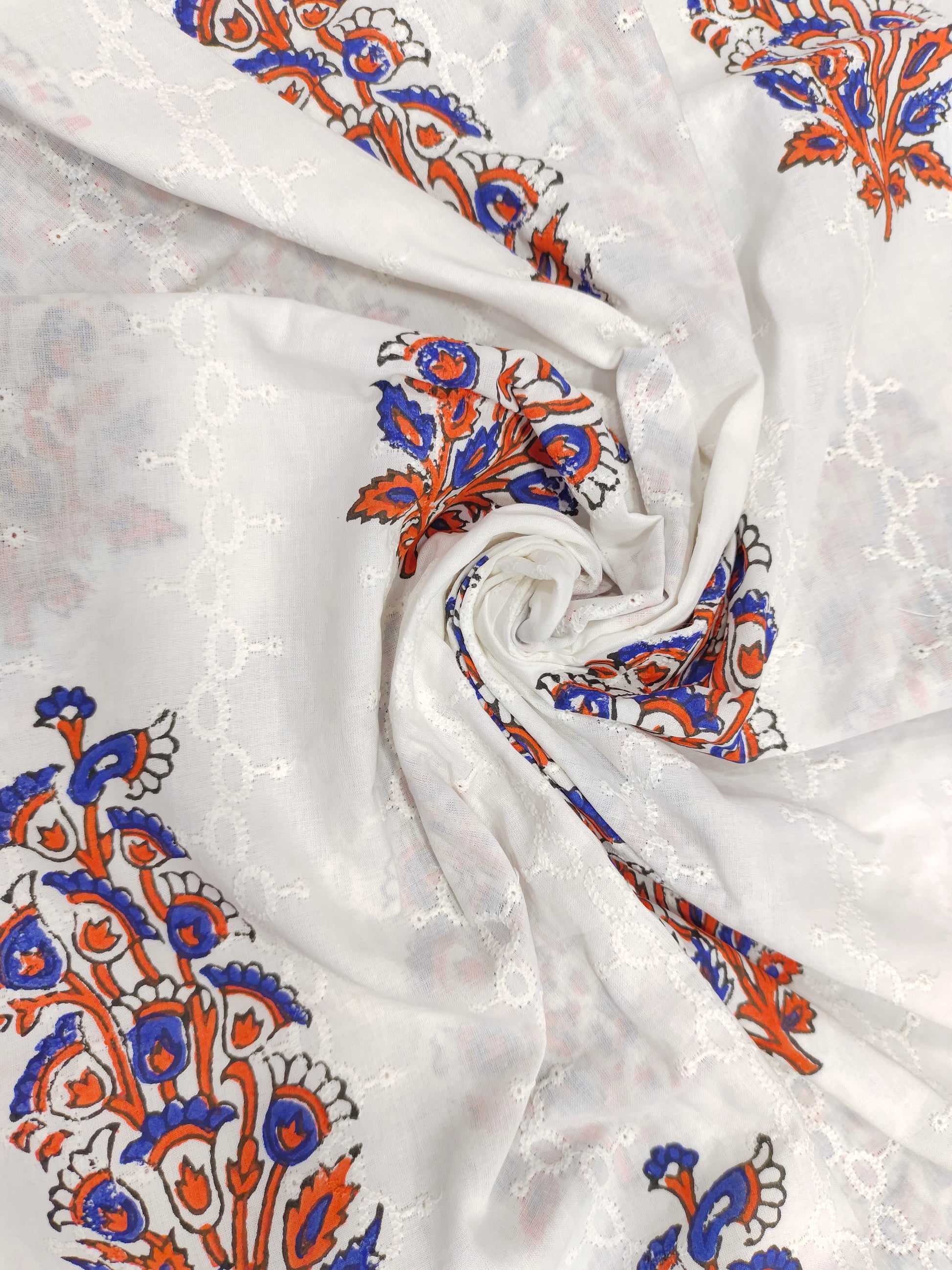 White embroidered fabric with blue and orange handblock print
