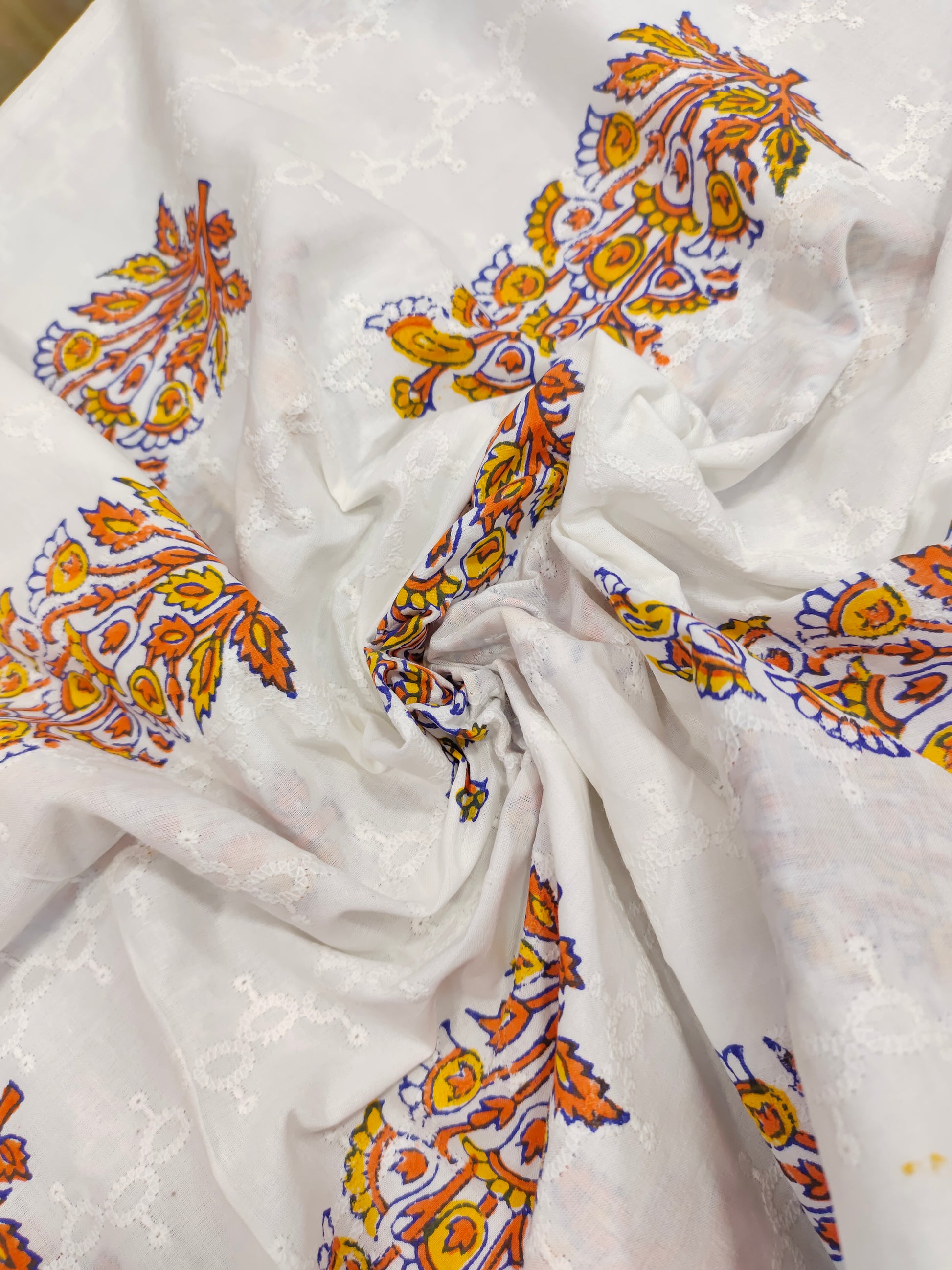 White embroidered fabric with orange handblock print