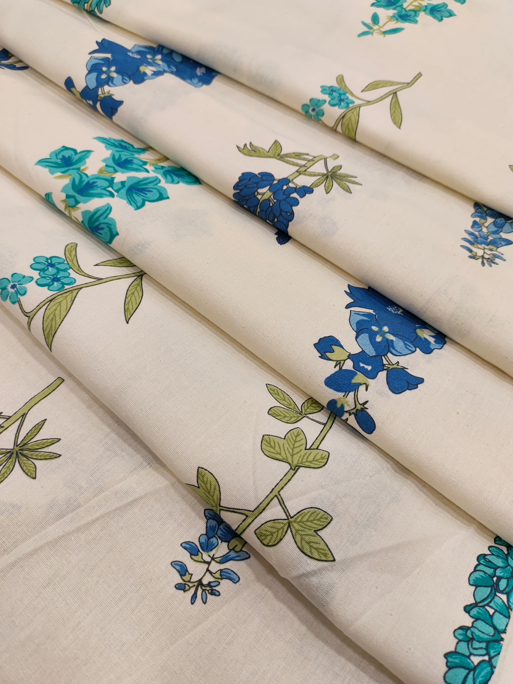 Cream cotton flex fabric stem type print with blue and green.
