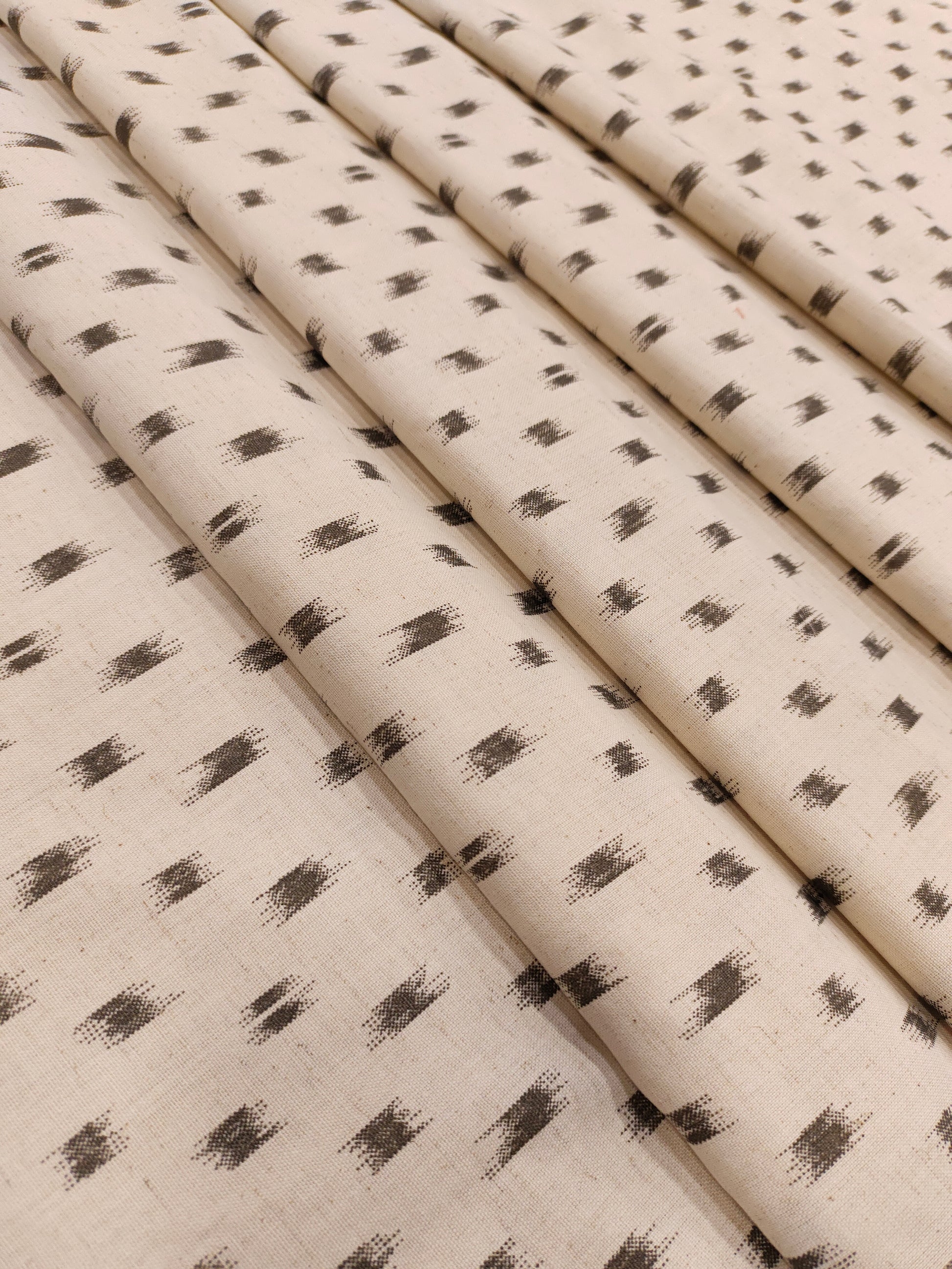 Flex cotton ikkat type print in grey color on cream fabric.