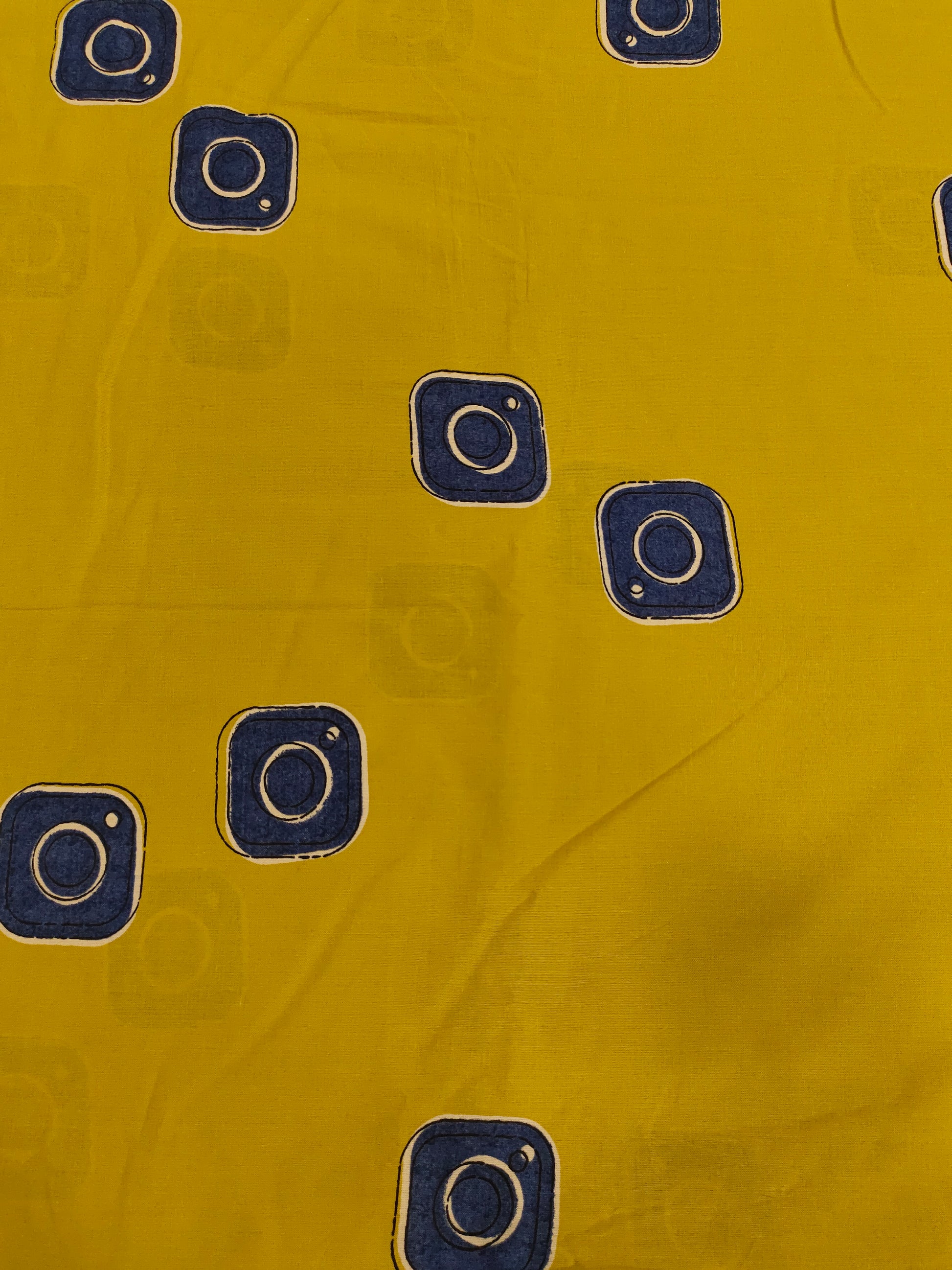 Cotton mustard fabric discharge print with blue in abstract design.
