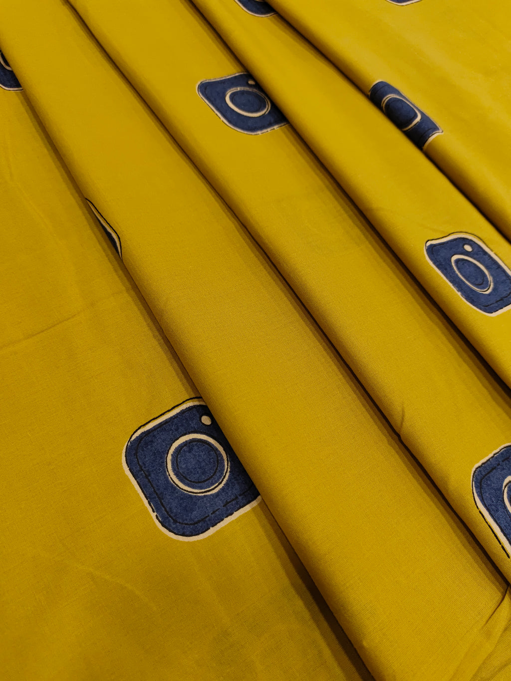 Cotton mustard fabric discharge print with blue in abstract design.