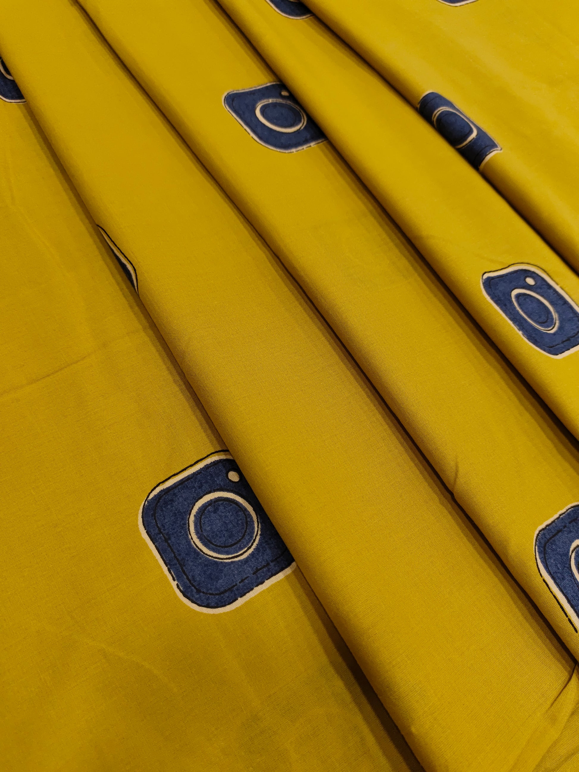 Cotton mustard fabric discharge print with blue in abstract design.