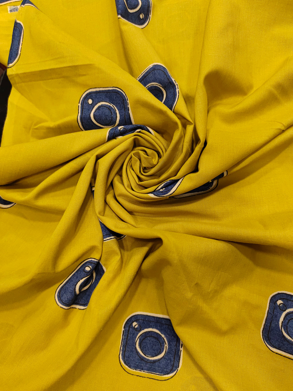 Cotton mustard fabric discharge print with blue in abstract design.