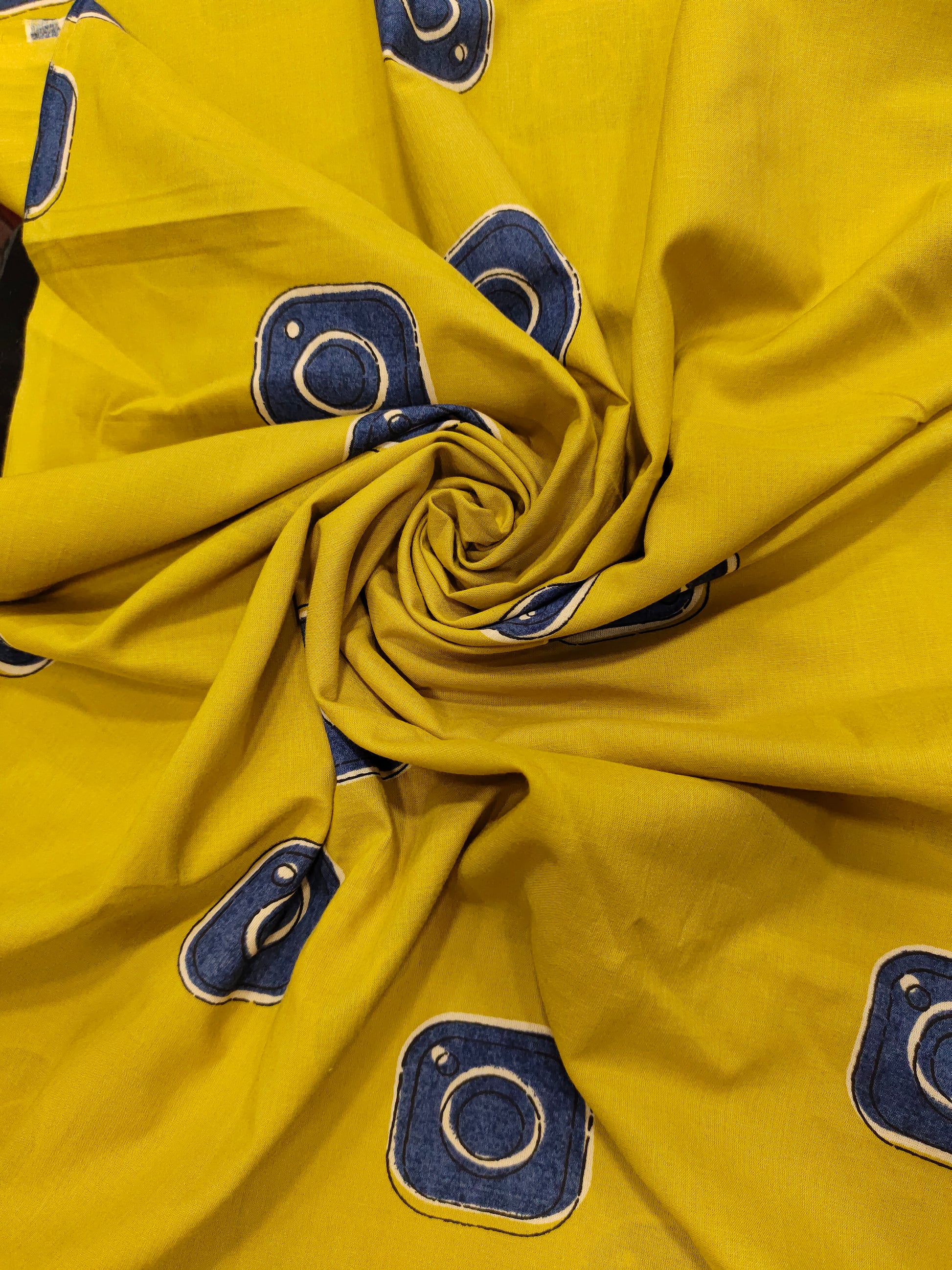 Cotton mustard fabric discharge print with blue in abstract design.