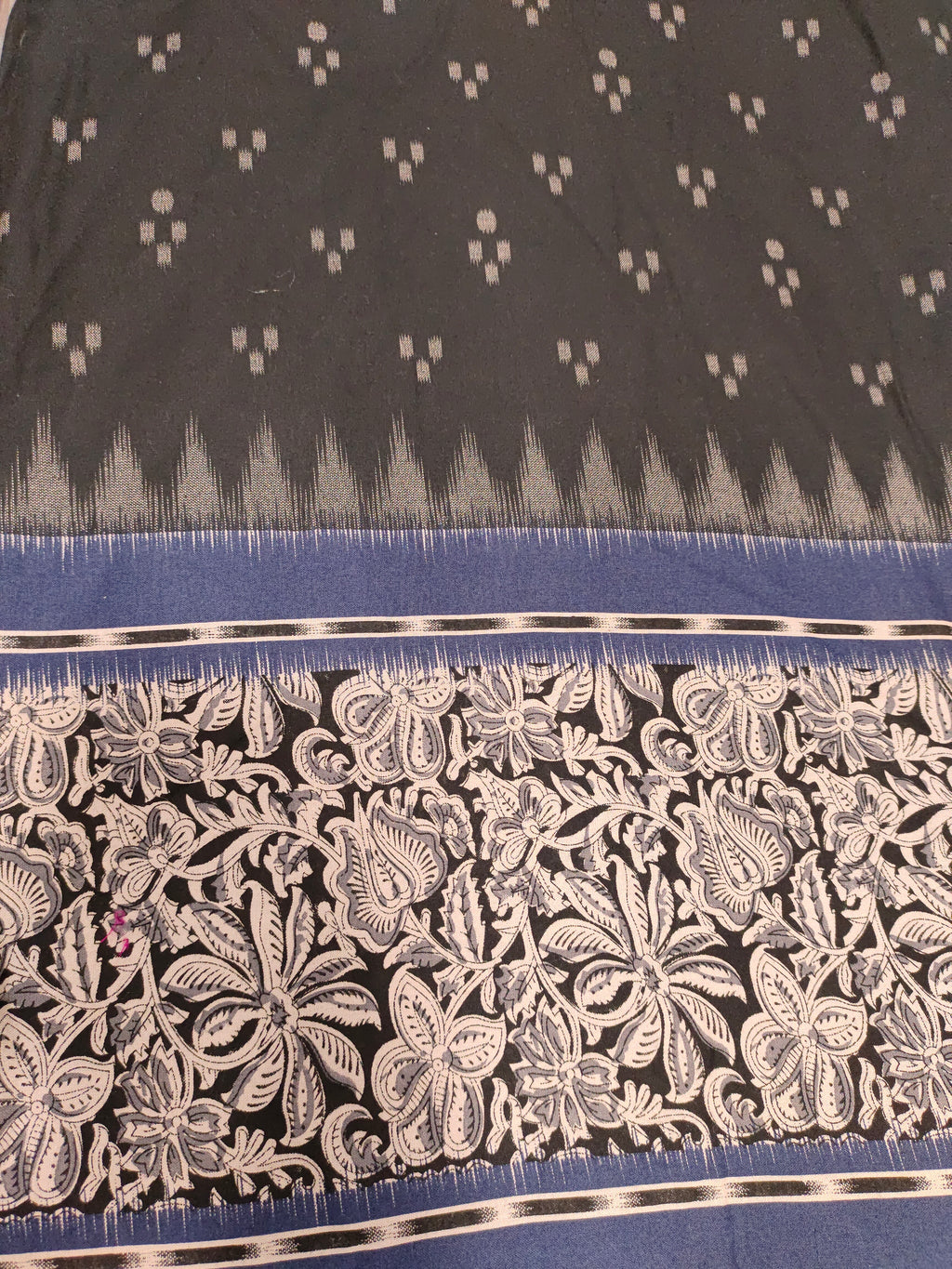 Black cotton fabric with blue daman print in hand.