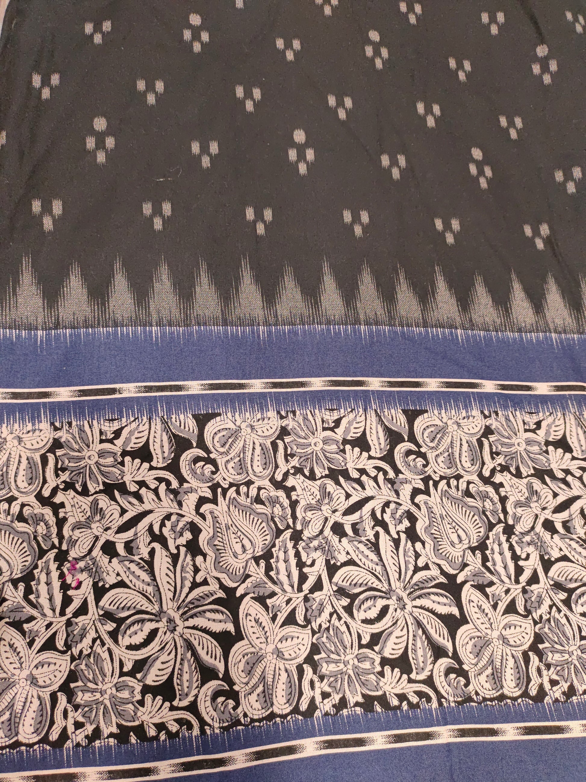 Black cotton fabric with blue daman print in hand.