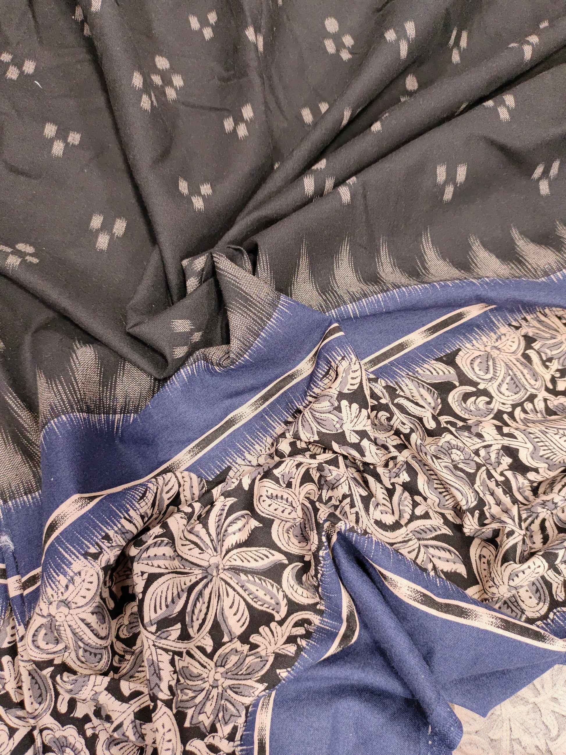 Black cotton fabric with blue daman print in hand.