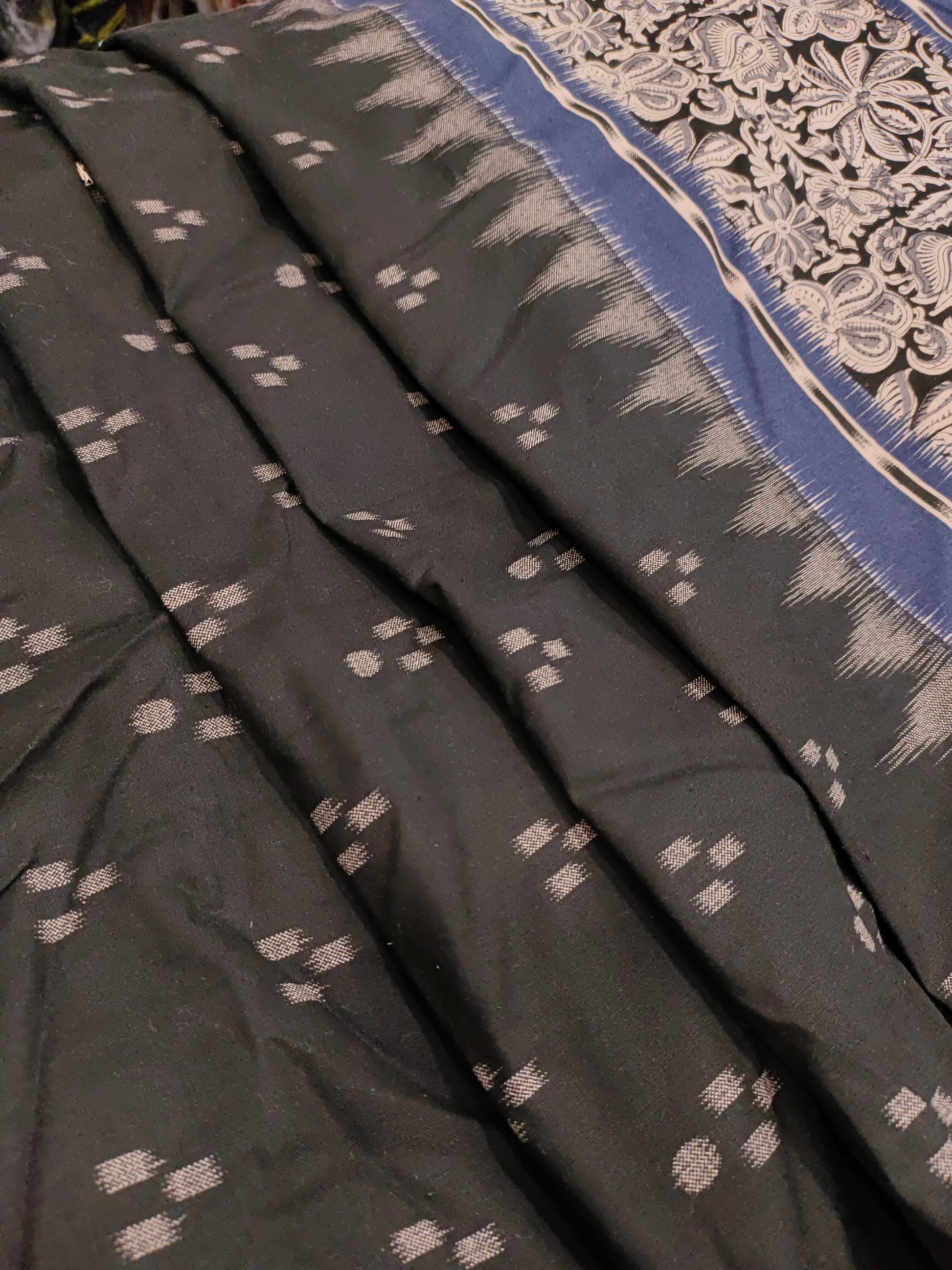 Black cotton fabric with blue daman print in hand.