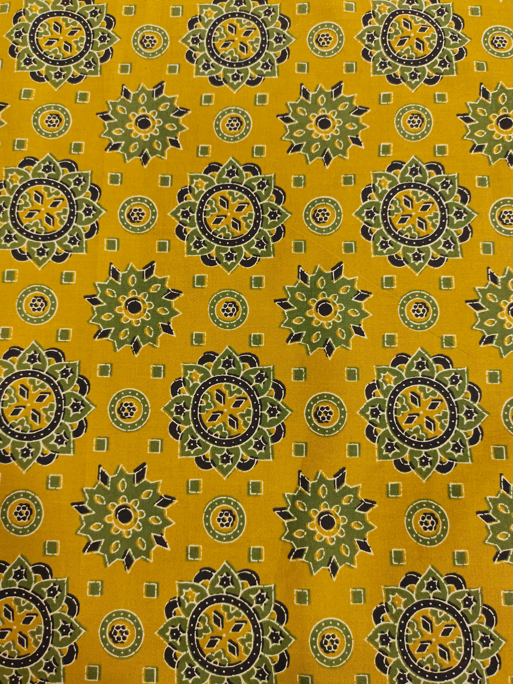 Mustard base cotton screen print with green black and off white traditional motifs.