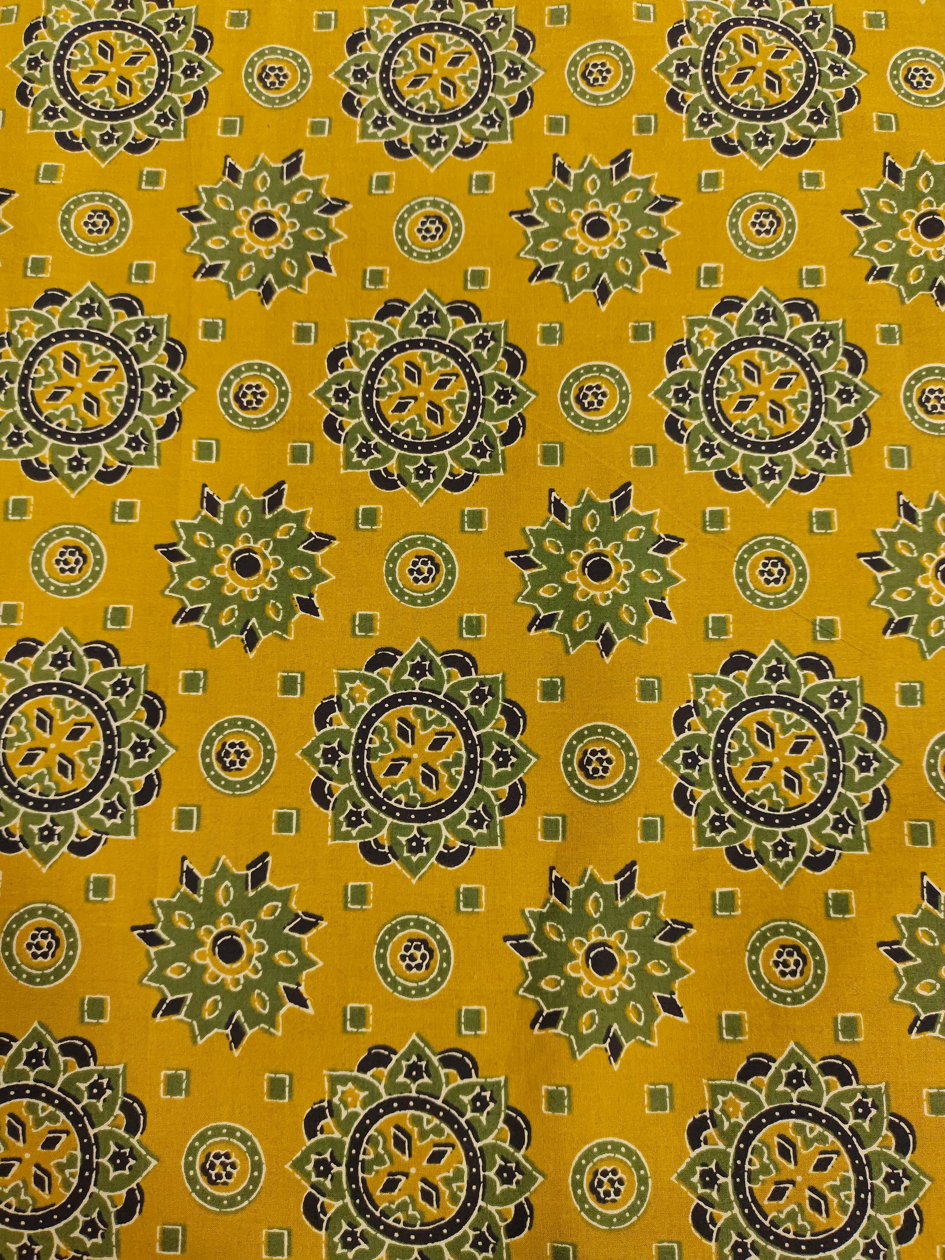 Mustard base cotton screen print with green black and off white traditional motifs.