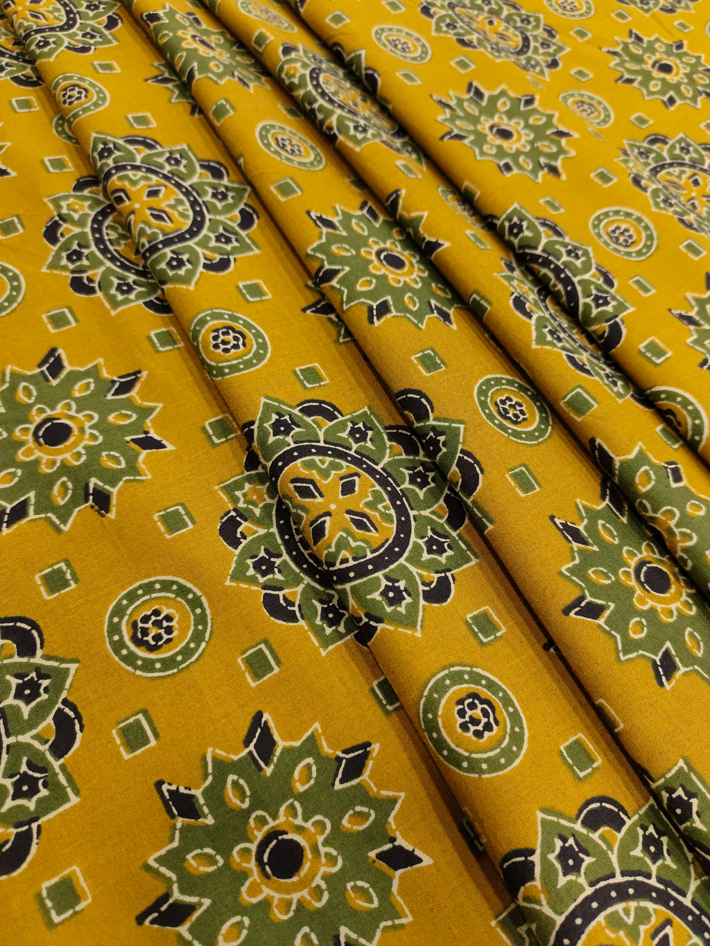 Mustard base cotton screen print with green black and off white traditional motifs.