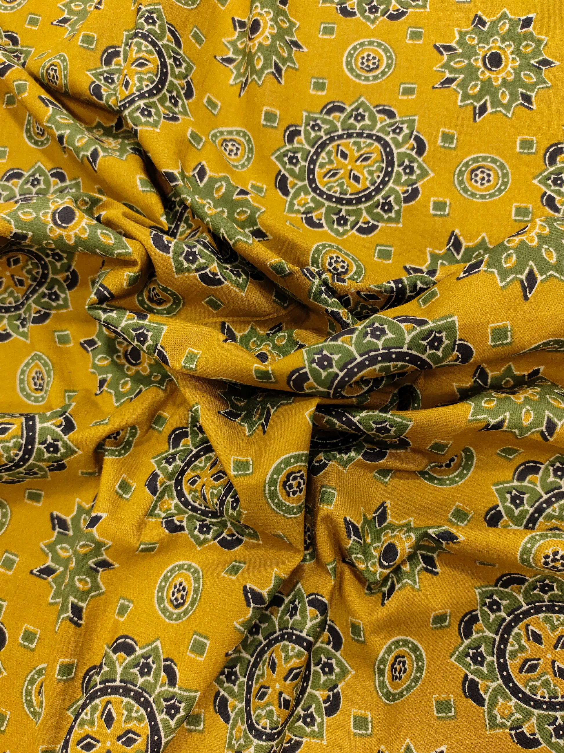 Mustard base cotton screen print with green black and off white traditional motifs.