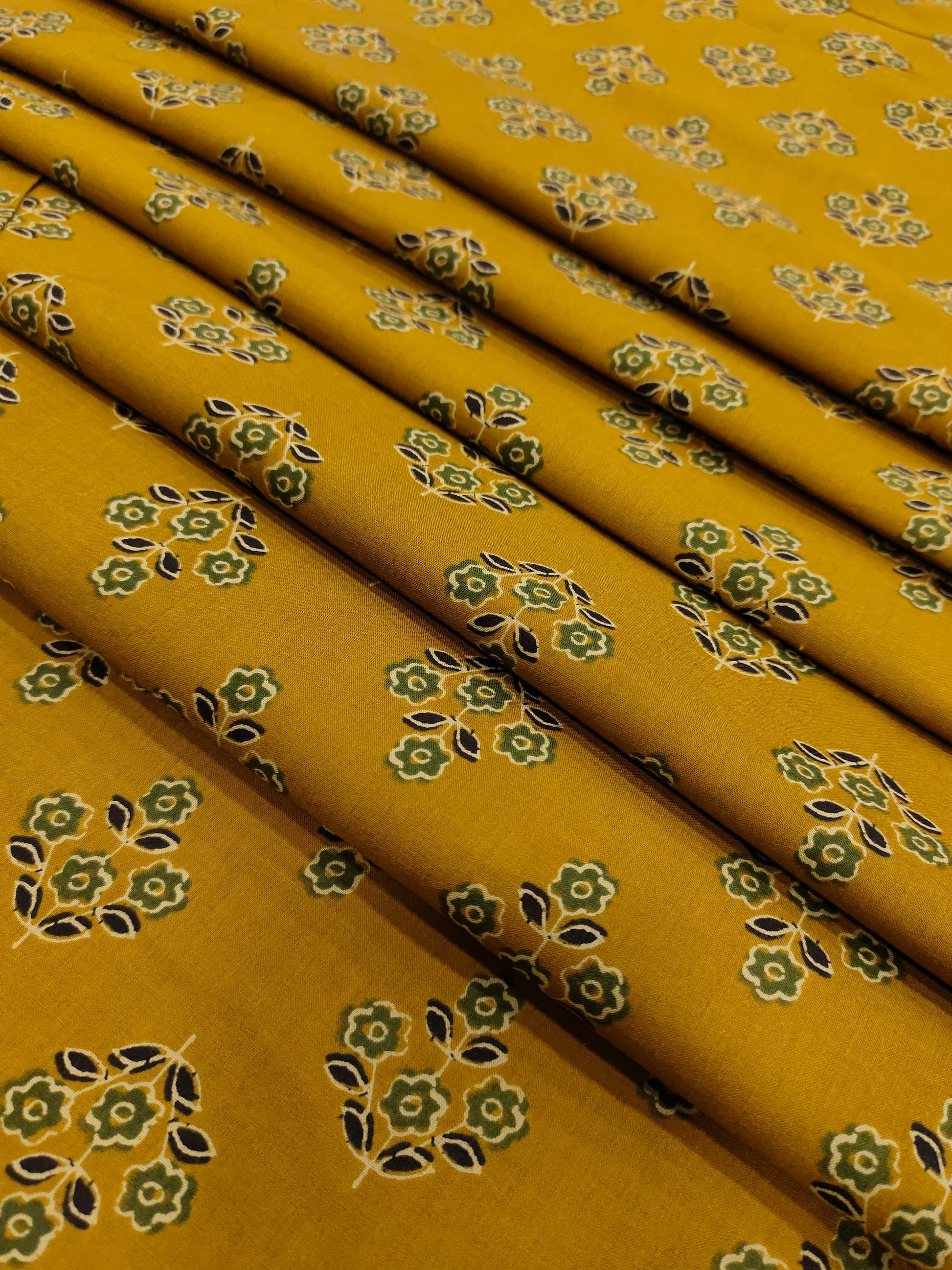 mustard cotton fabric with green black and beige butti.