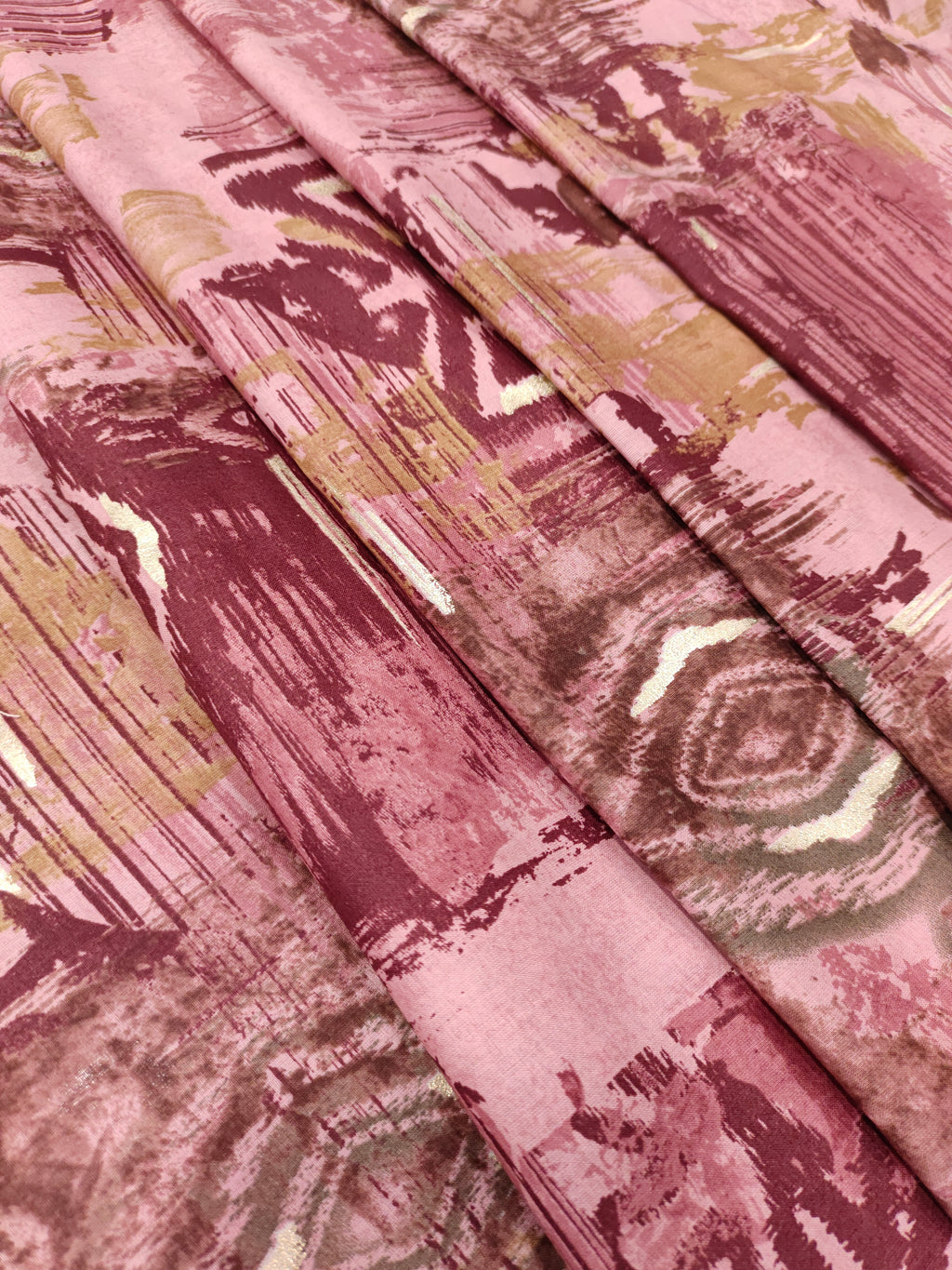 Cotton abstract print with little gold foil in maroon and pink colors.