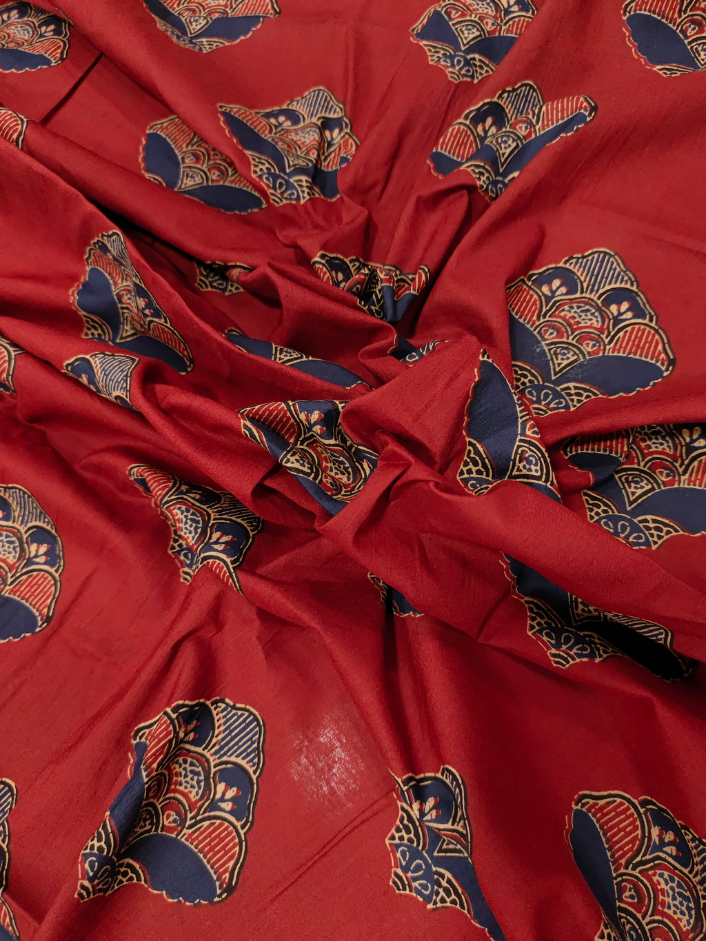Maroon cotton fabric with floral motifs in blue and beige.