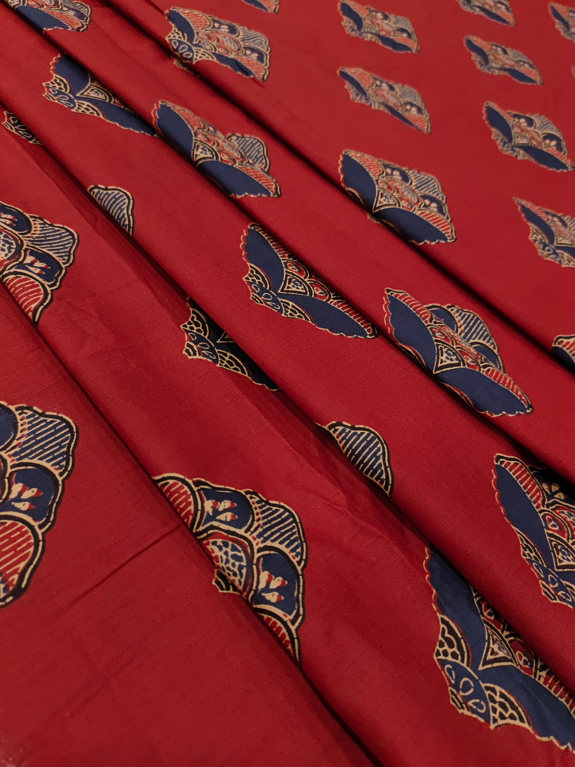 Maroon cotton fabric with floral motifs in blue and beige.